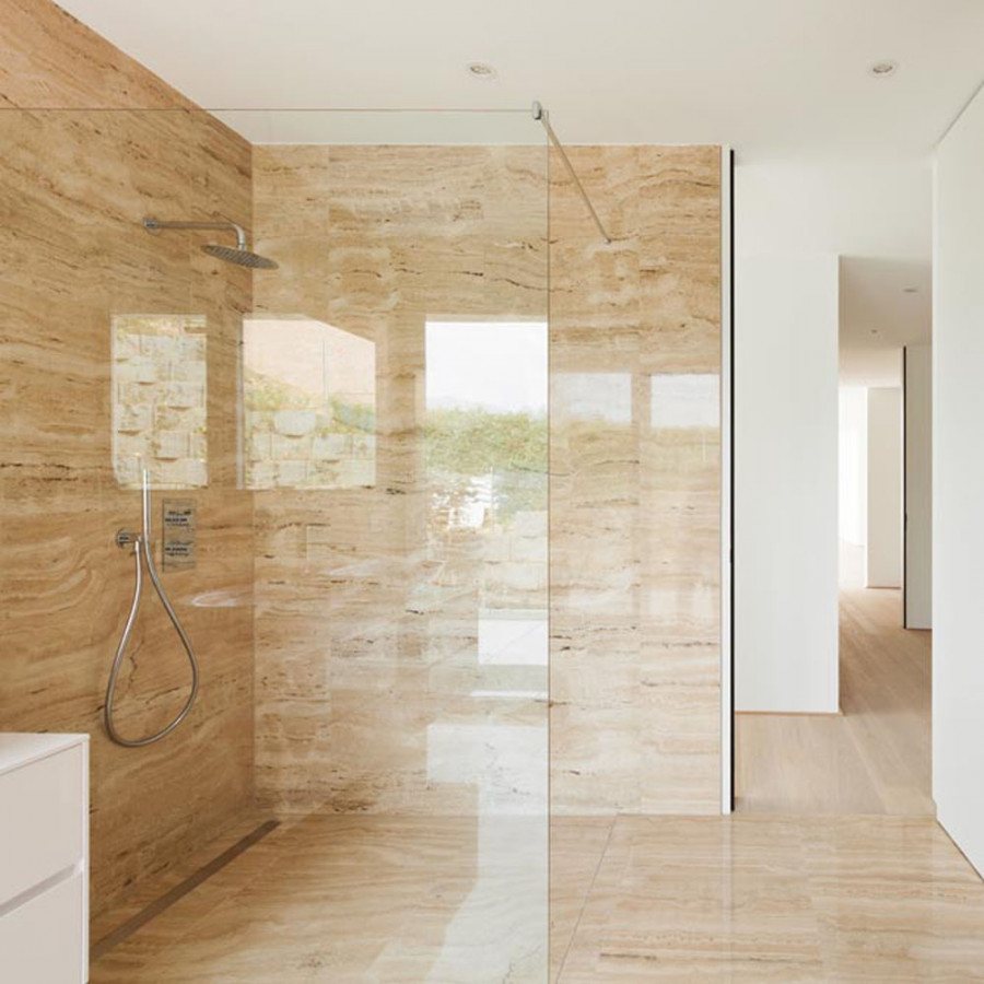 Mampara transparente con herrajes discretos en un baño de piedra clara, imagen de Rue du Verre